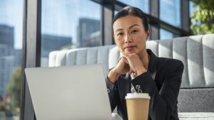 Woman with an open laptop and takeaway coffee in an office