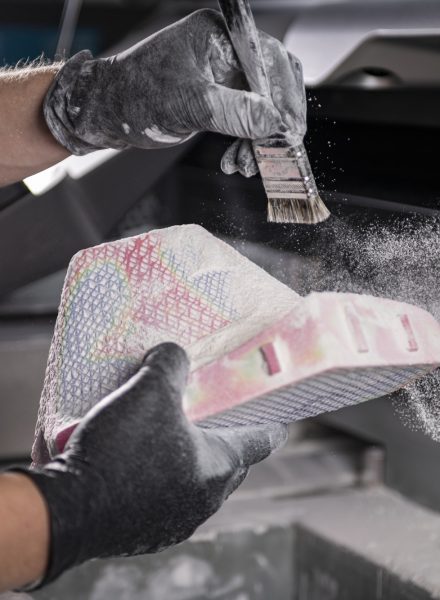 two hands cleaning a recently 3d printed item with a brush