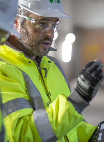 Construction worker with a tablet giving instructions to an unseen person