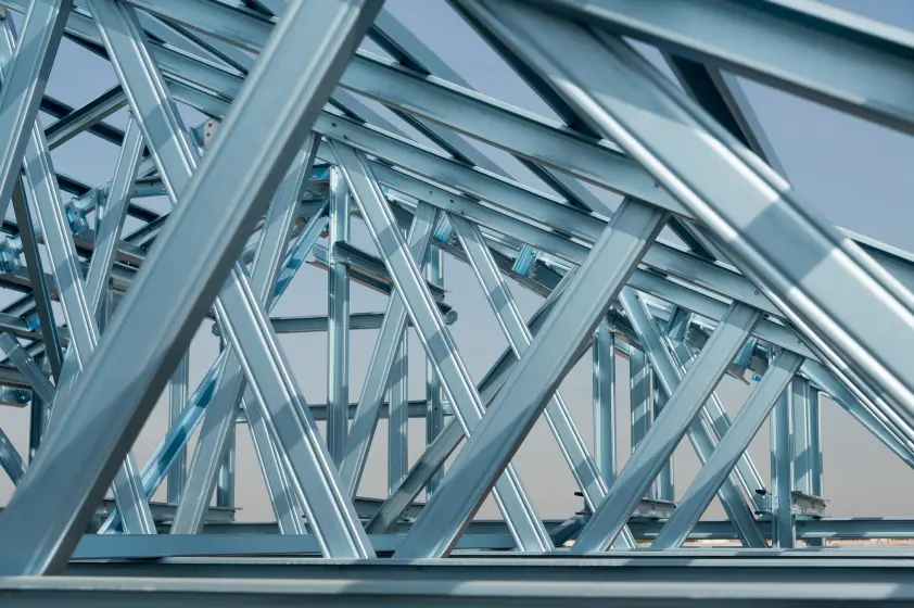 Abstract architectural photo that shows angled, intersecting beams supporting a large, angled skylight