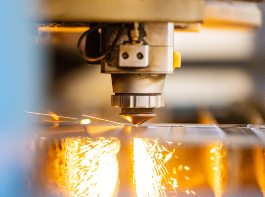 Close-up of a precision CNC cutter in action, generating bright sparks as it cuts metal sheets.