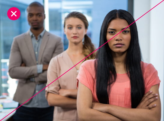 3 office workers stand in a staggered line, crossing their arms and looking overly serious. The image feels overly posed, with unnatural expressions, and is marked with a red X.