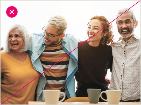 4 people stand, arms around each-other, over a table with a few teacups. The image is marked with a red X, since the focus is not on product outcomes