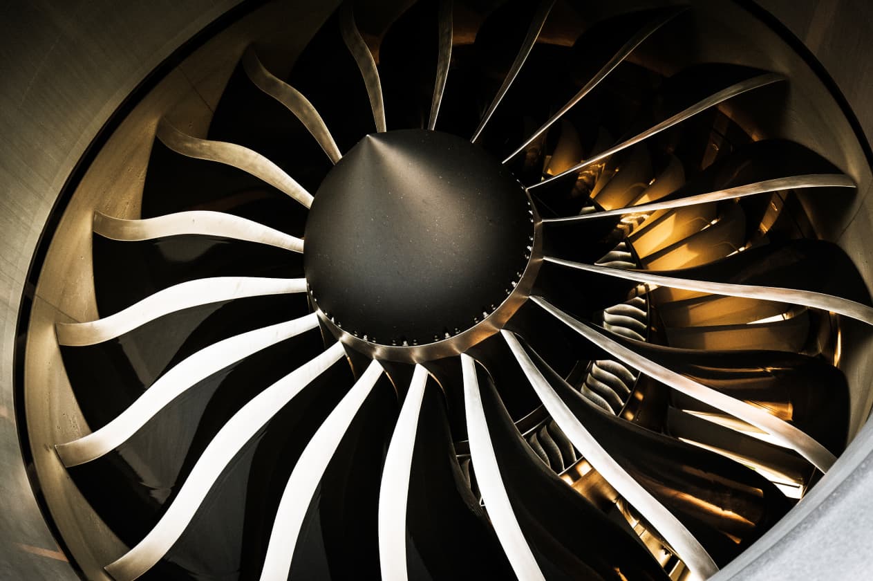 Close-up photo of a large industrial turbine, highlighting the abstract, sculptural form of its blades