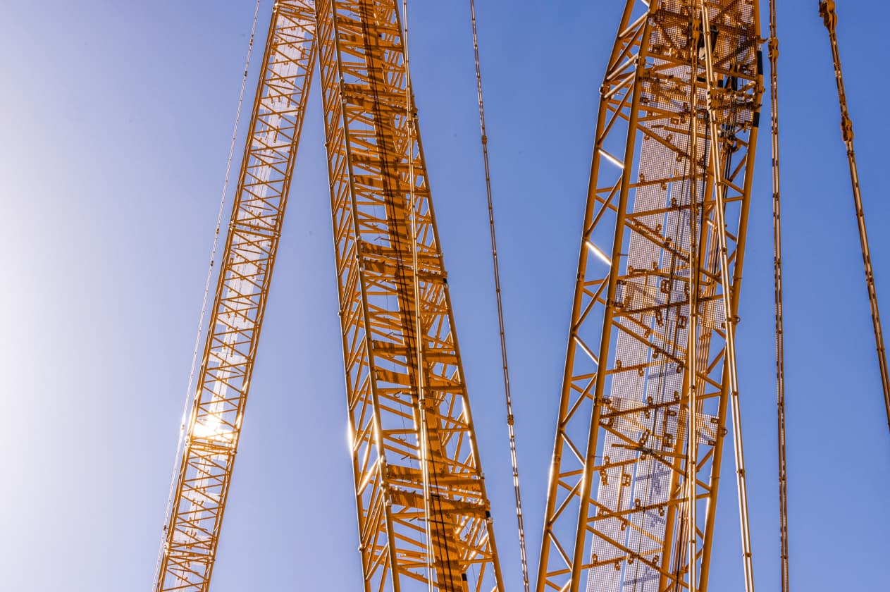 Abstract close-up photo of yellow crane gantries criss-crossing over a blue sky