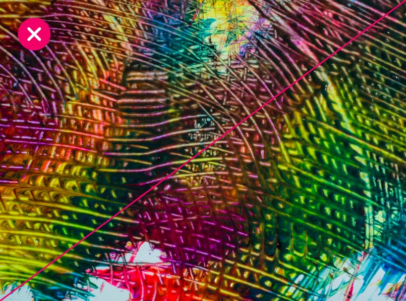 A complex, abstract diffraction pattern shimmers in green, yellow, blue, and purple tones, looking almost like a painting. The image is marked with a red X.